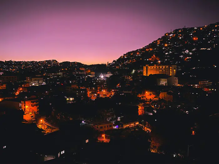 Baguio's hillside houses lighting up at dusk under a pink sky