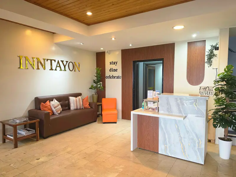 Inn-tayon's lobby with the gold INNTAYON sign, a leather sofa and a marble front desk