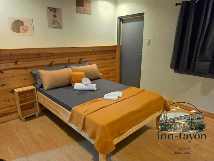 Couples Room with a pine-wood double bed, grey linens, an orange throw and rolled towels
