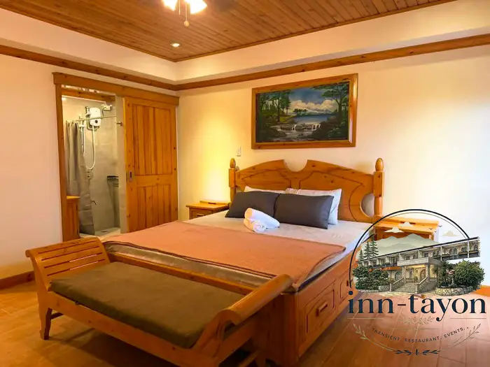 Executive Suite with a carved wooden king-size bed, a bench at its foot, a framed landscape painting and its own bathroom