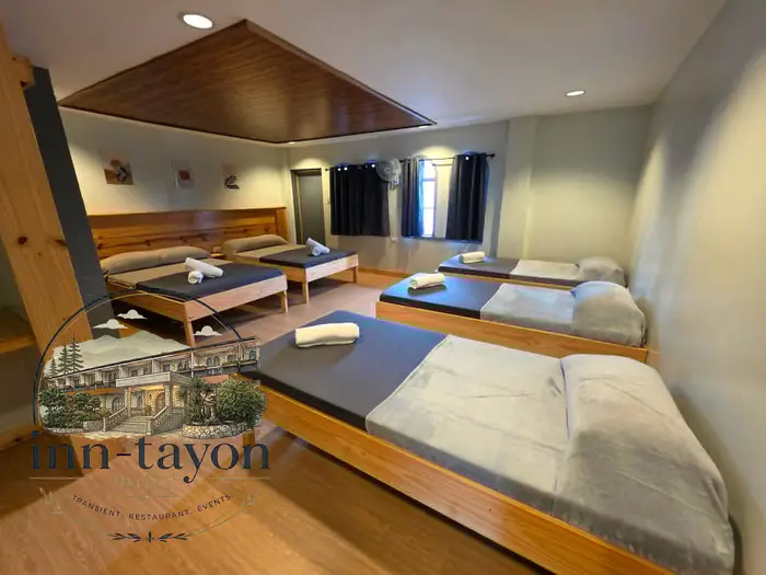 Family Room D with four wooden beds, grey linens and dark curtains